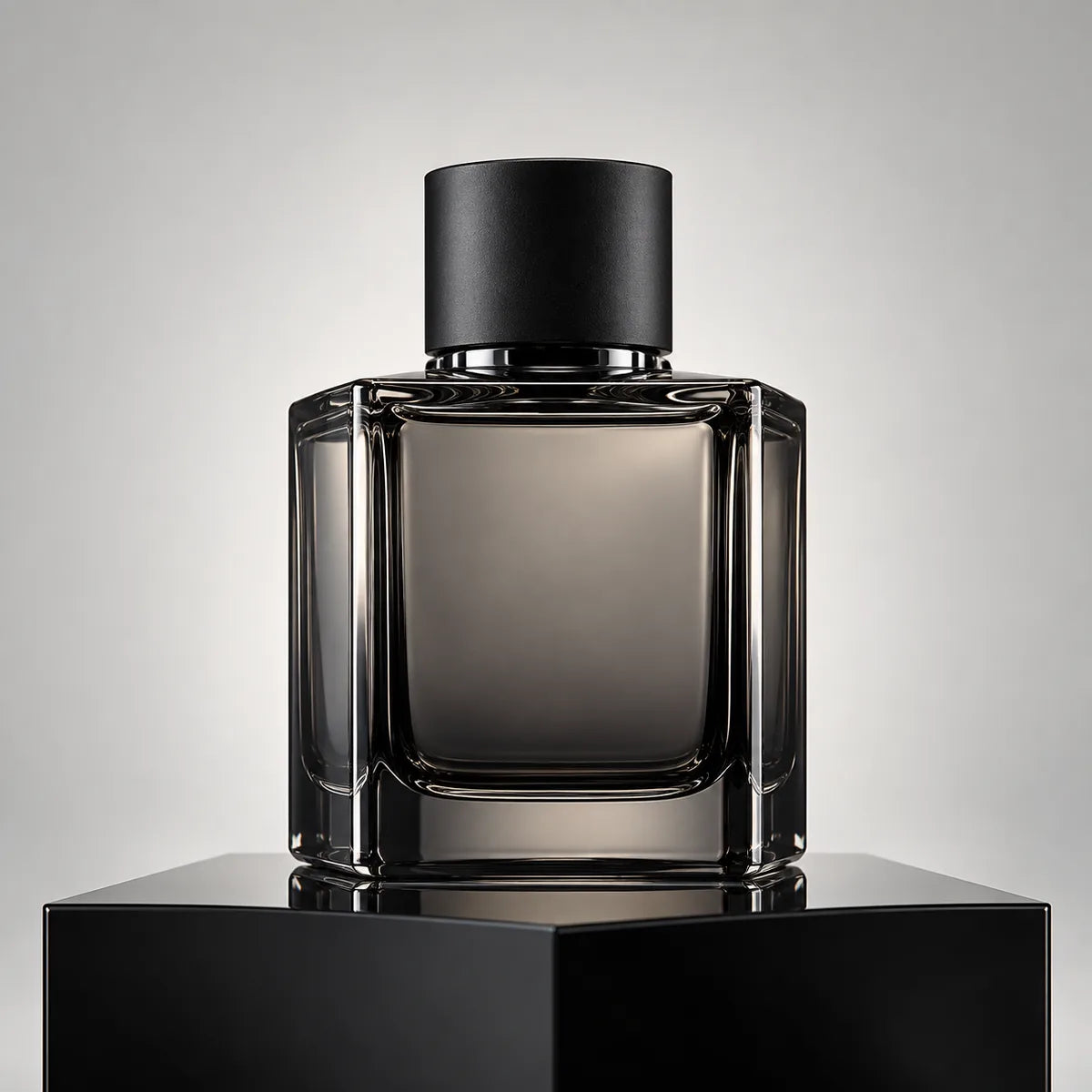 A squat smoked grey glass perfume bottle with a matte black cap on a black block